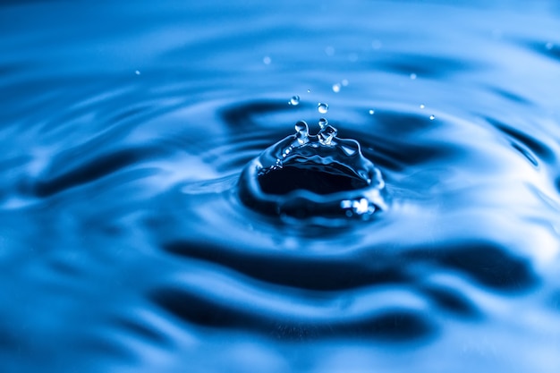 Water drop splash in a glass blue colored