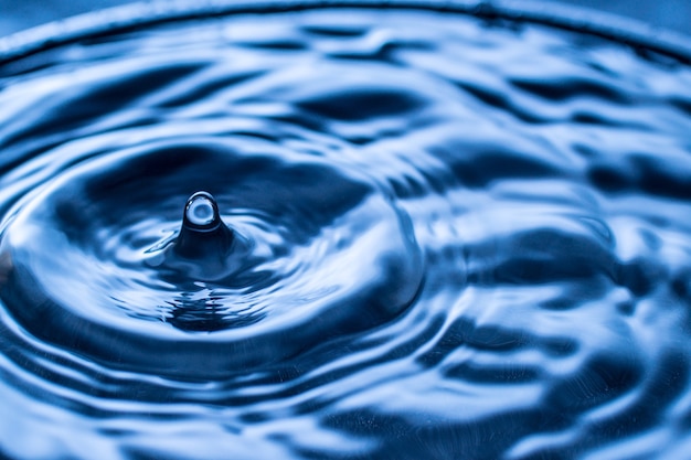 Water drop splash in a glass blue colored