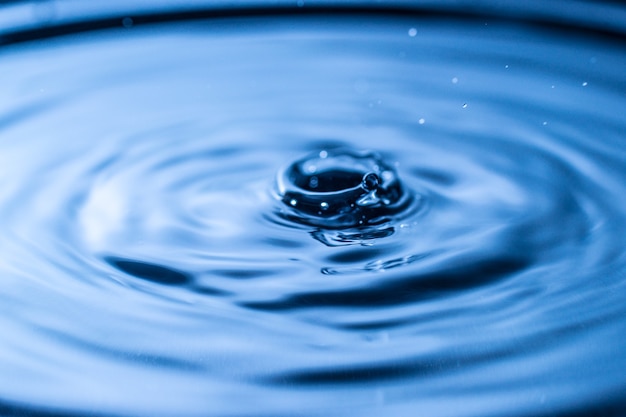 Water drop splash in a glass blue colored