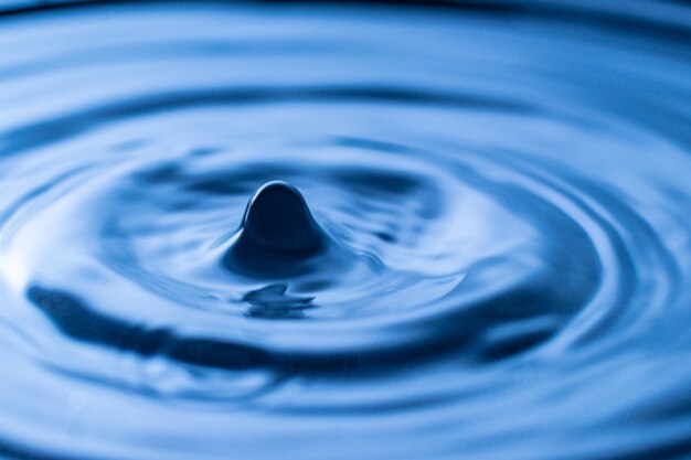 Water drop splash in a glass blue colored