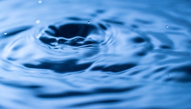 Water drop splash in a glass blue colored