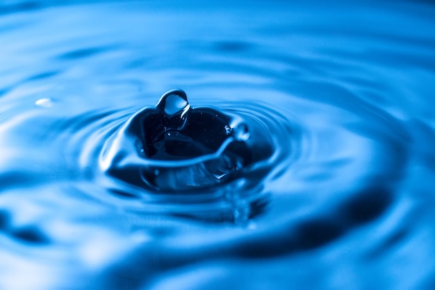 Water drop splash in a glass blue colored