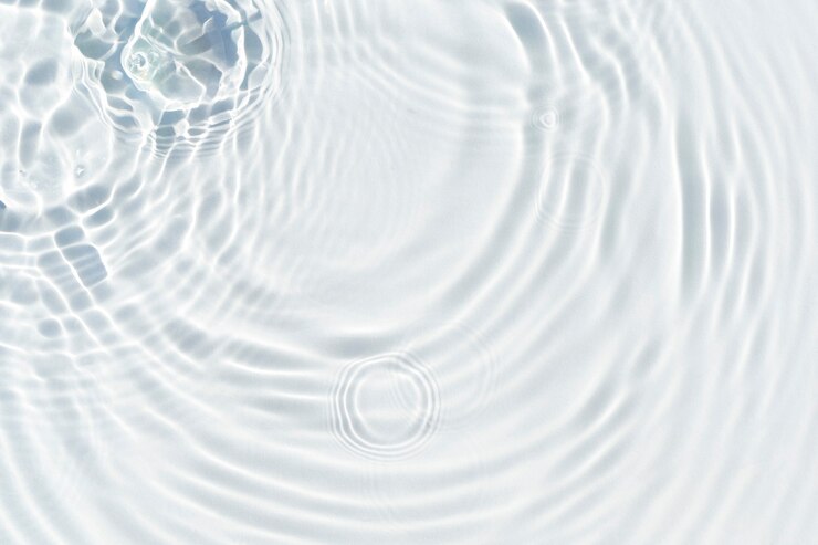Photo water droplets fall on the transparent surface of the water in sunlight. top view, flat lay.