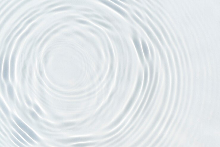 Photo water droplets fall on the transparent surface of the water in sunlight. top view, flat lay.