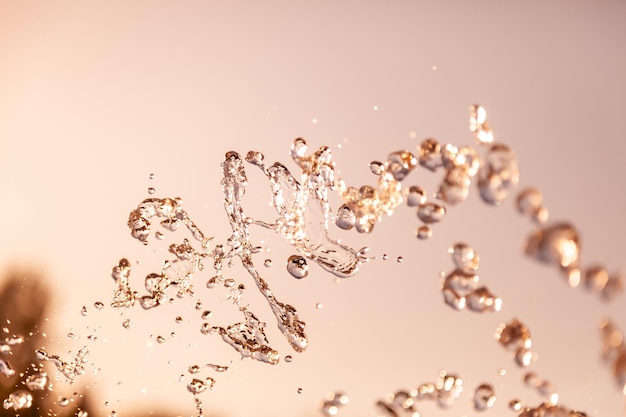 Water droplets frozen in the air with splashes and chain bubbles on a golden and bronze isolated background in nature Clear and transparent liquid symbolizing health and nature