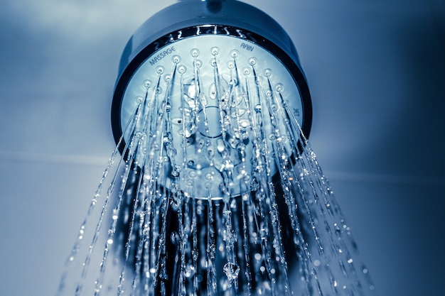 Water drops close-up dripping from the shower blue filtered