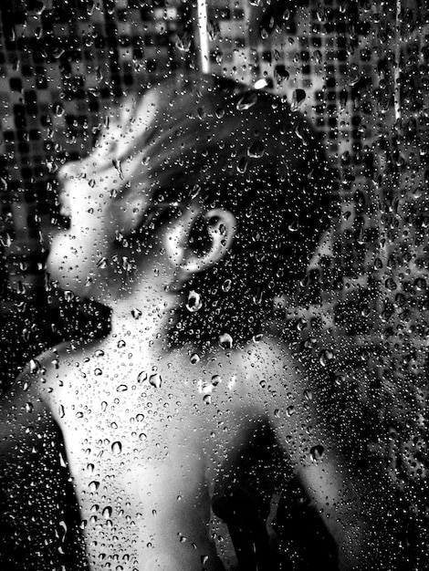 Photo water drops on glass against boy bathing in bathroom