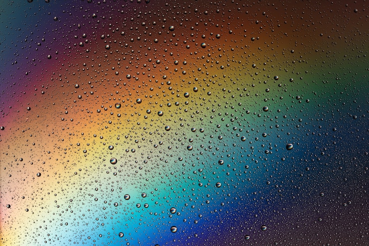 Фотография капли воды на стекле с эффектом радуги