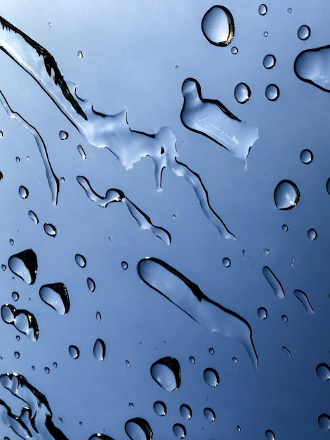 Капли воды в движении через окно после дождя