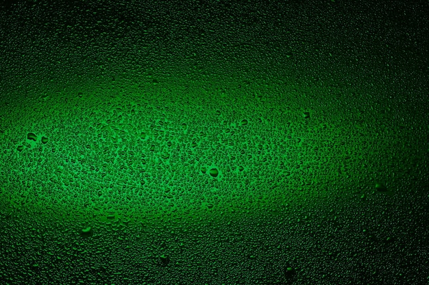 写真 黒いガラスに水滴。緑で照らされた背景