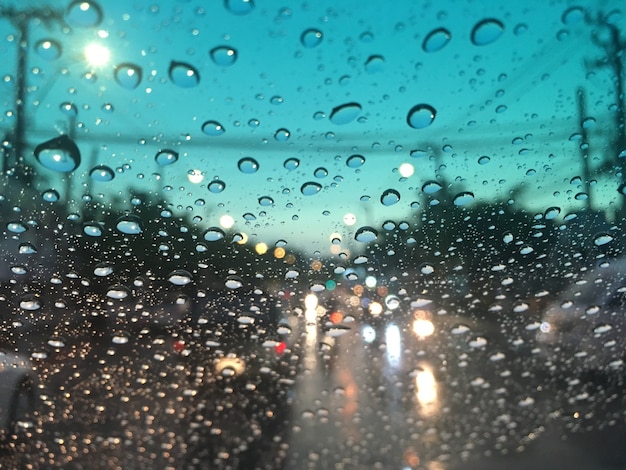 Фото Вода падает на лобовое стекло, движение в городе в дождливый день, красочные боке.