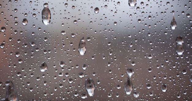 ガラス上の水滴または氷片。秋の涼しい雨天。閉じる。
