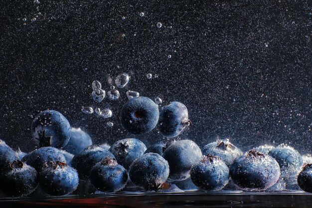 Water drops on ripe sweet blueberry. Fresh blueberries background with copy space for your text. Vegan and vegetarian concept. Macro texture of blueberry berries.