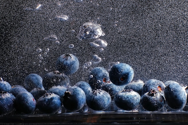 Water drops on ripe sweet blueberry. Fresh blueberries background with copy space for your text. Vegan and vegetarian concept. Macro texture of blueberry berries.