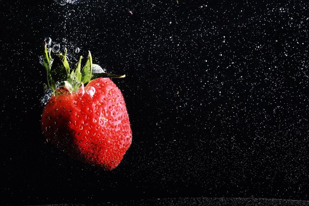 Water drops on ripe sweet strawberry. Fresh berry background with copy space for your text. Vegan food concept.