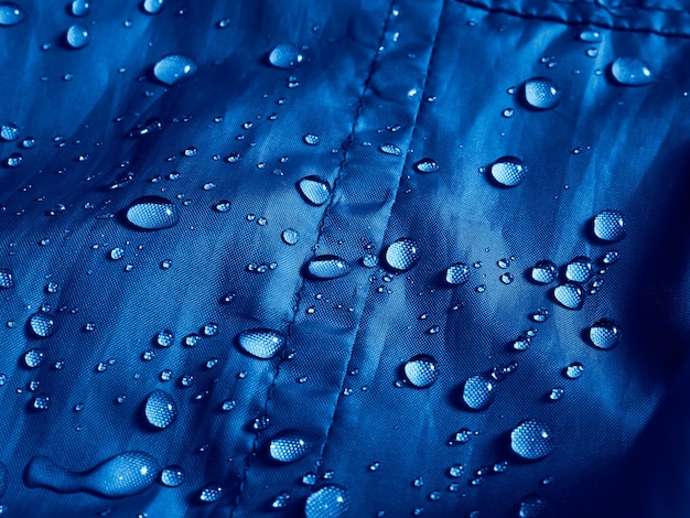 Water drops on waterproof membrane fabric. Detail view of texture of blue waterproof cloth.