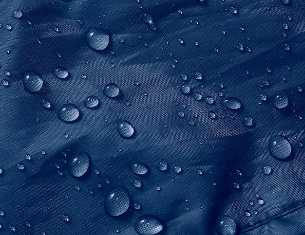 Gocce d'acqua su tessuto a membrana impermeabile. vista in dettaglio della trama del panno impermeabile blu.