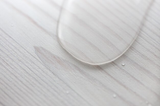 Water drops on white wooden surface made from larch wood covering by oil with wax.