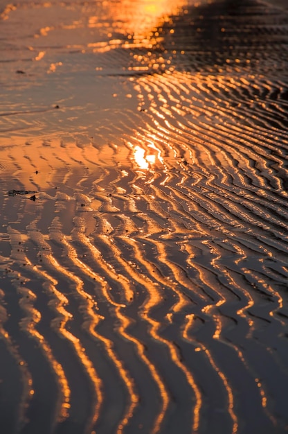 Water en zand op het strand in zonsondergangtijd