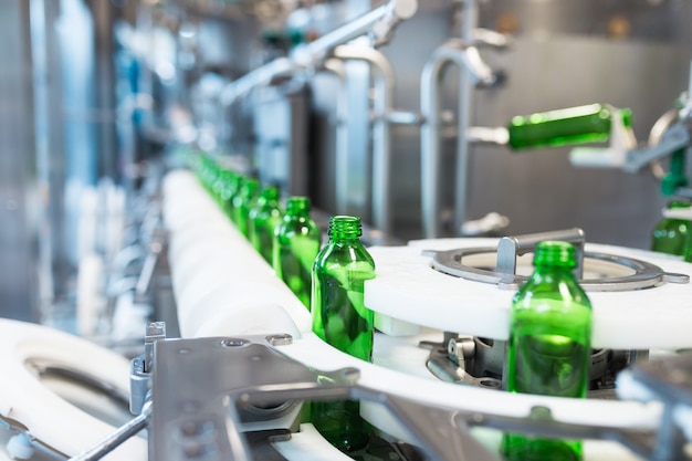 Water factory - Water bottling line for processing and bottling pure mineral water into small green glass bottles. Selective focus.