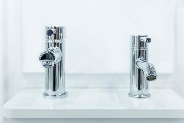 Water faucets on the sink in a stylish white interior\
exhibition of samples front view closeup selective focus