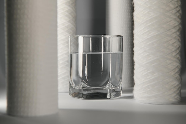 Фото Фильтры для воды угольные картриджи и стакан на белом фоне бытовая система фильтрации