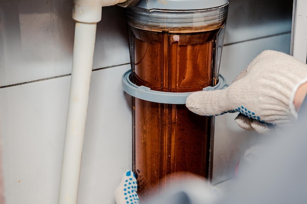 Water filtration - the plumber changes the dirty water filter. Cleaning of tap water.