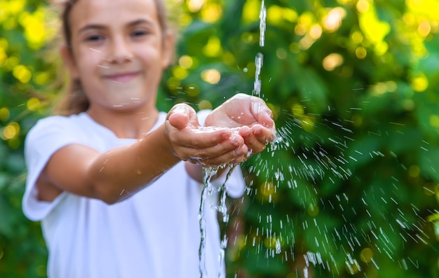 水は子供の手に流れ込みます。セレクティブフォーカス。自然。