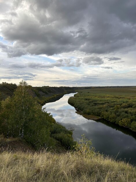 Вода течет через травянистое поле под облачным небом в естественном ландшафте