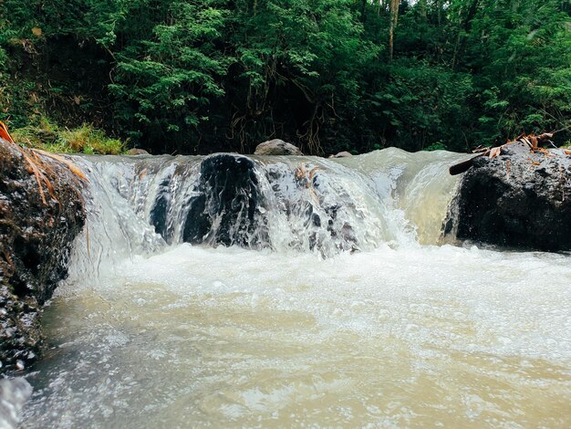 Water from a lake under a waterfall overflows a rock