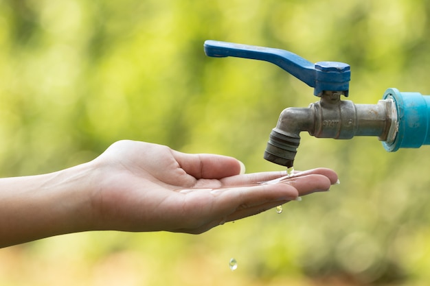 Water from tab pouring in hand on nature 