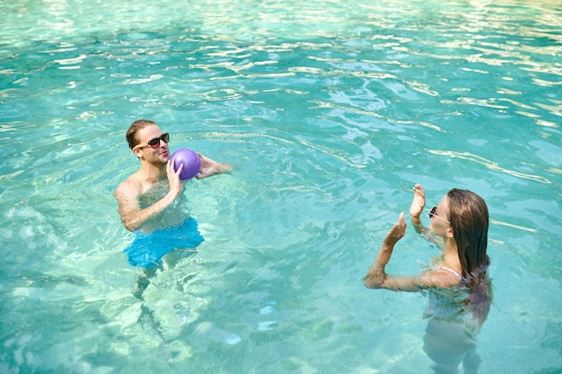 Water game. a man and a womna playing ball in a swimming\
pool