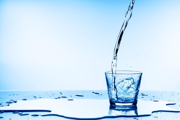Water gieten in glas op blauwe achtergrond
