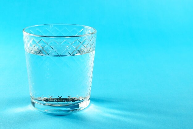 Water in glass against blue background with copy space