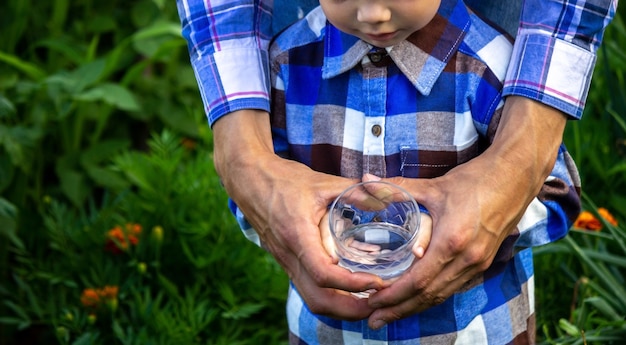 子供と父親の手にあるグラスの中の水。自然。