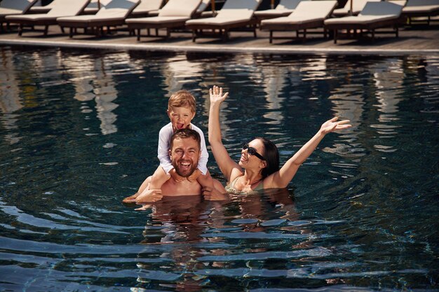 Photo in the water happy family of father mother and son are in the pool