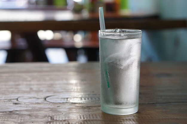 Acqua e ghiaccio in un bicchiere appoggiato su un tavolo di legno