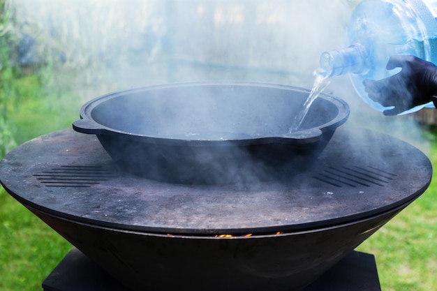 Water is added to the cauldron to boil the soup The boiler stands on a metal grill Horizontal photo