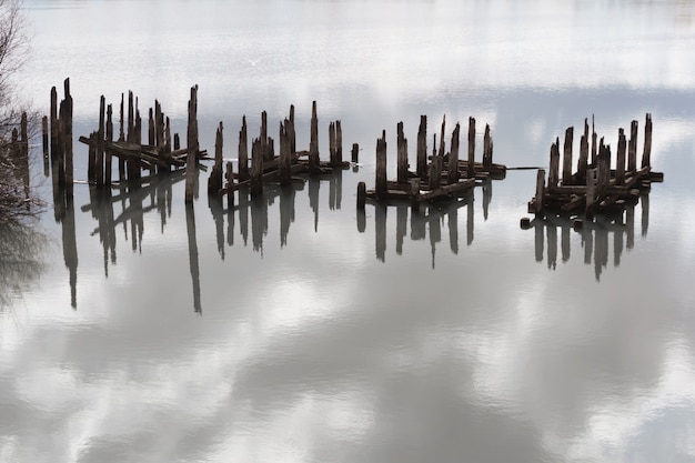 Water landscape with fragments of piles of destroyed bridge reminiscent of unknown hieroglyphs