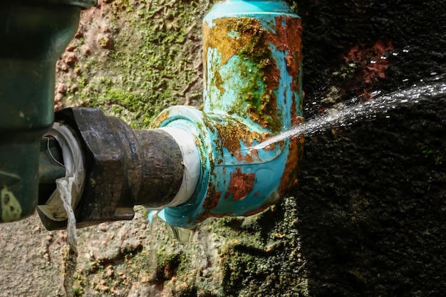 Water leaks from a long-used blue plumbing pipe. Selective focus to Water leaks crack.