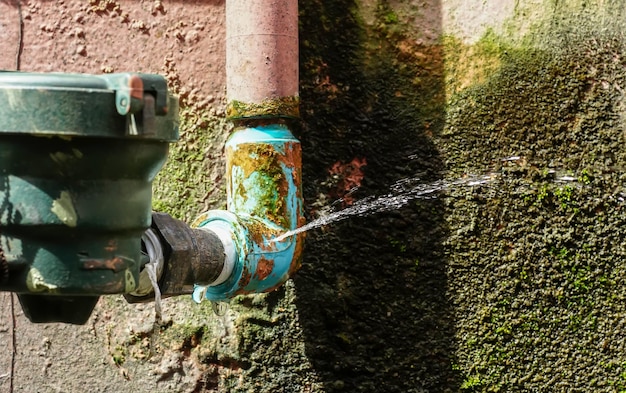 Water leaks from a long-used blue plumbing pipe.