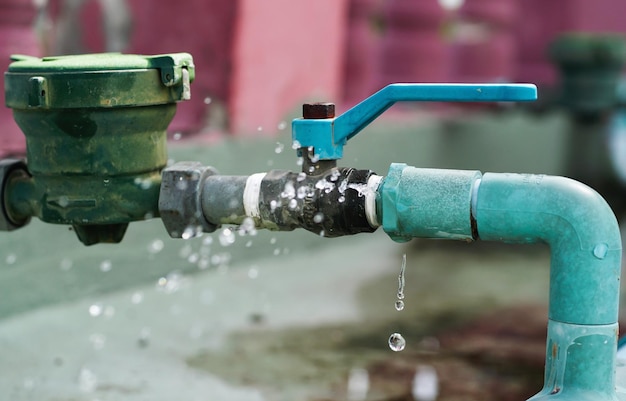 Water leaks water drop from a long-used blue plumbing pipe.\
selective focus to water leaks.