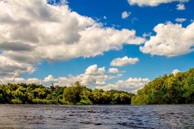 water level on a wide river and a wooded shore