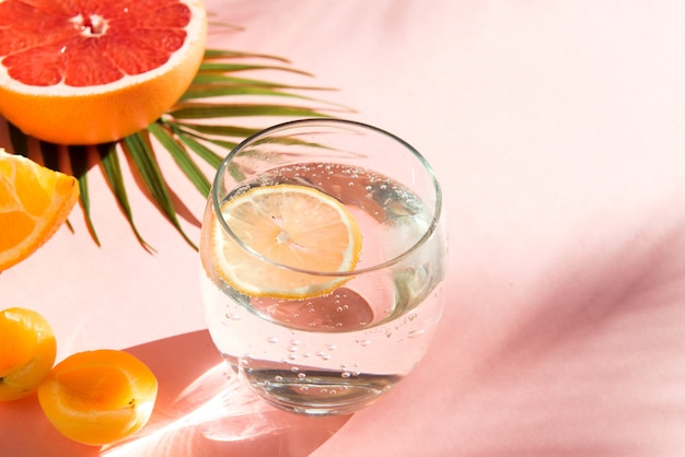 water met ijs en citroen koele zomerdranken gezond voedsel fruit en frisdrankglas op roze kleur backg