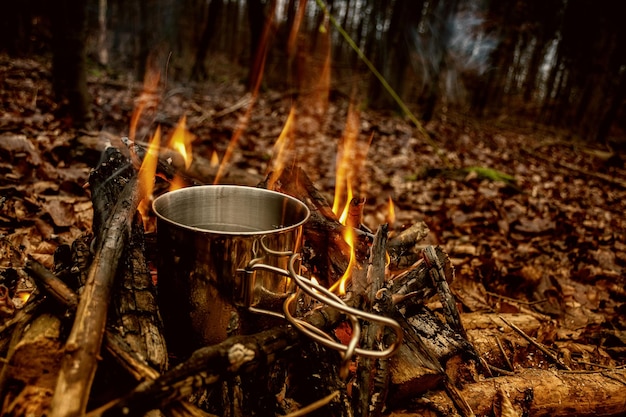 Water in metallic container on campfire at forest