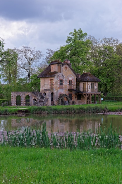 写真 フランスのパリのヴェルサイユ宮殿にあるマリーアントワネットの古い村の湖にある水車小屋。