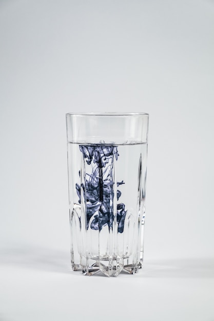 Photo water pollution concept. dark substance contaminating clean water in a glass