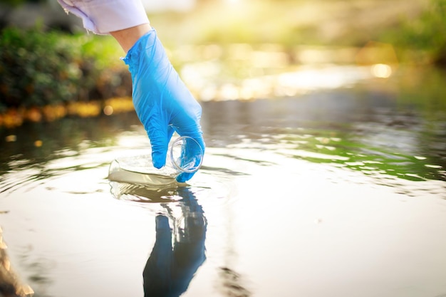 Water pollution in the pond river lake sea concept Scientist takes samples of factory wastewater in a test tube Close up the hand