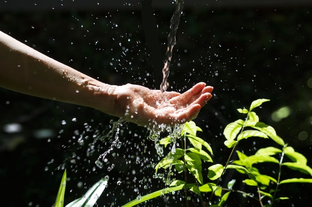 Вода, наливание в руку женщины на фоне природы, вопросы окружающей среды.