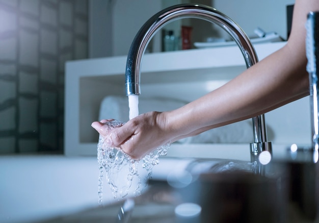 女性の手に水が注ぐ。